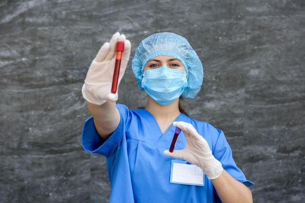 Medizinischer Arbeiter, der rotes Reagenzglas hält und im Labor darauf schaut