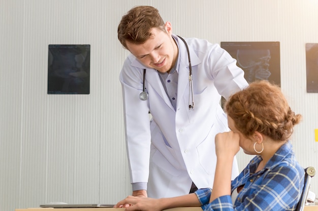 Medizinischer Mann, der den jungen Patienten der jungen Frau versichert und spricht.