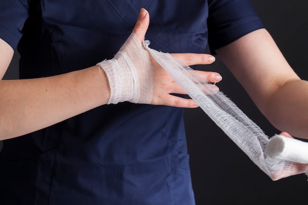 Medizinischer weißer Verband in den Händen einer Ärztin, ein Mann in medizinischer Kleidung hält einen weißen Verband in den Händen, um Beulen zu behandeln