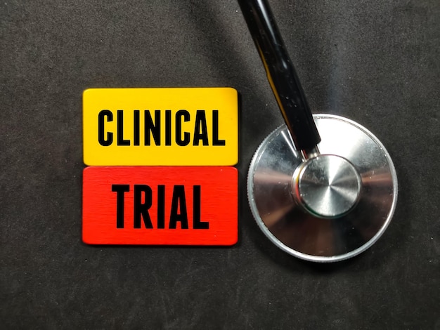 Medizinisches KonzeptText KLINISCHE STUDIE auf farbigem Holzbrett mit Stethoskop auf schwarzem Hintergrund schreiben