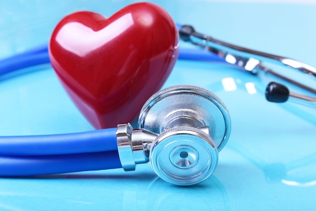 Medizinisches Stethoskop und rotes Herz lokalisiert auf blauem Spiegelhintergrund