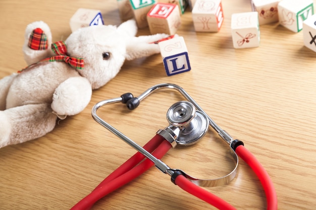 Medizinisches Stethoskop und Spielzeug auf Holzuntergrund
