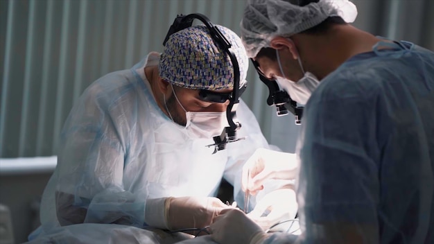 Medizinisches Team führt eine Operation durch, in der die Gesichter von Chirurgen mit Ferngläsern in der Nähe gezeigt werden.