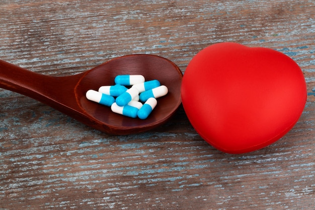 Medizinpillen, Tabletten und Kapseln auf Holzlöffel mit Herz.
