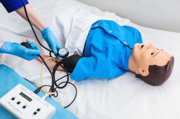 Medizinstudent misst den Blutdruck an einem Dummy. Ausbildung in der ärztlichen Praxis im Ausbildungskrankenhaus