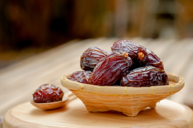 Medjool fechas o dátiles fruta en canasta de madera y cuchara en la mesa