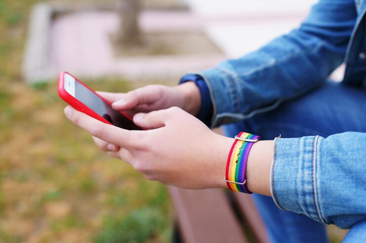 Foto meek con arco iris lgtb pulsera escribiendo en el teléfono móvil