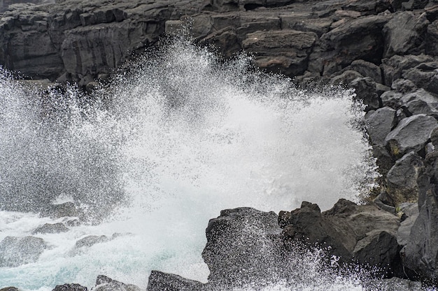 Meer im Sturm brechende Wellen auf Lavafelsen