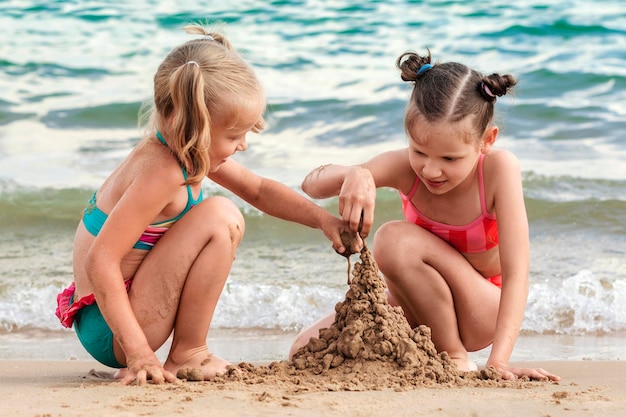 Meer Sommer Spaß Urlaub Glückliche Kinder bauen Sandburg und spielen am Meeressandstrand