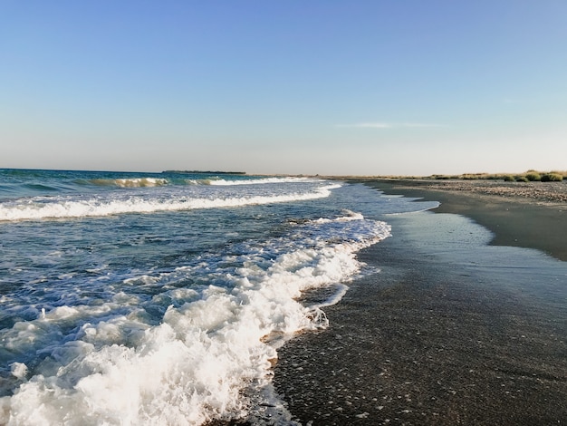 Meerblaue Aquamarinwellen säumen sonnigen Sandstrand. weiche Welle von Ozeanschaum.