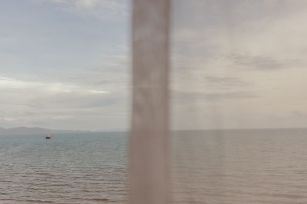 Meerblick durch dünnen weißen Vorhang im Sommer