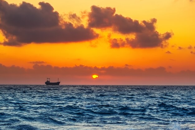 Meerblick mit Frachtschiff in der Sonnenuntergangzeit