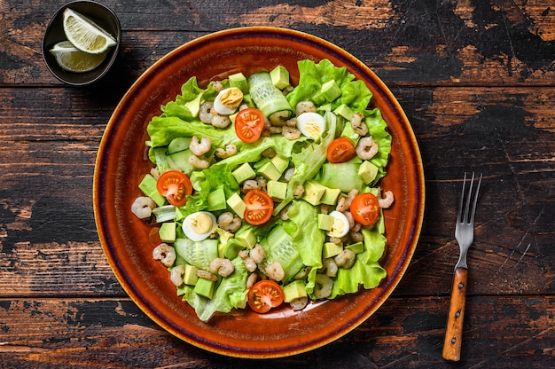 Meeresfrüchte-Avocado, Garnelen, Garnelensalat. Dunkler hölzerner Hintergrund. Draufsicht.