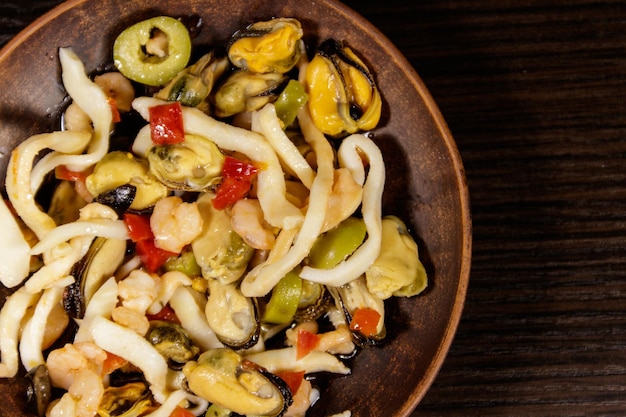 Meeresfrüchtesalat mit Garnelen, Tintenfisch und Muscheln auf Holztisch