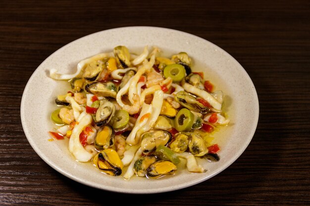 Meeresfrüchtesalat mit Garnelen, Tintenfisch und Muscheln auf Holztisch