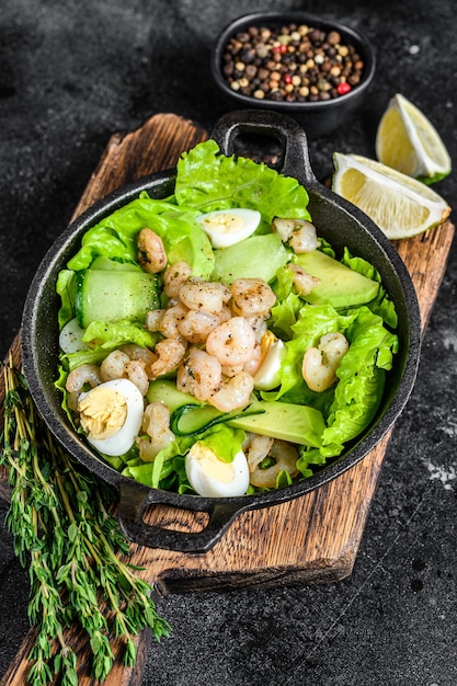 Meeresfrüchtesalat mit gegrillten garnelen, ei, avocado und gurke in einer pfanne.