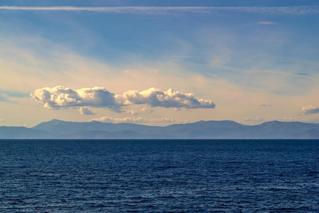 Meereslandschaft mit Bergen am Horizont und blauem Himmel mit Wolken