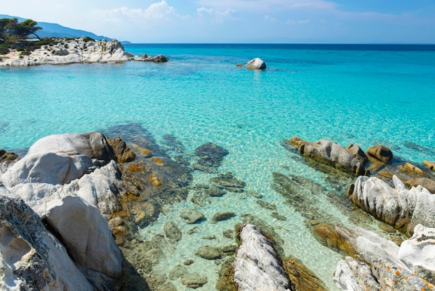 Meereslandschaft mit klarem türkisfarbenem Wasser zwischen Felsen und Steinen in der Ferne können Sie den Horizont sehen