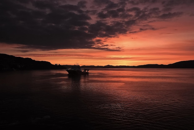 Meereslandschaft nach Sonnenuntergang in Bergen Norwegen Schiff im Meer in der Abenddämmerung Dramatischer Himmel über Sonnenuntergang Meerwasser Reisen mit Abenteuern per Schiff Sonnenaufgang Schönheit der Natur Fernweh und Urlaub