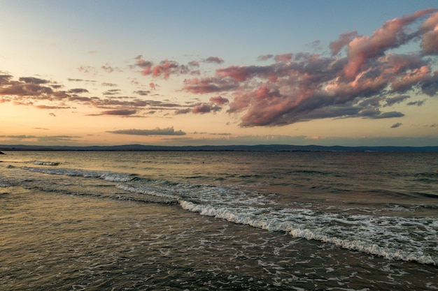 Meeresoberfläche mit blauen Wasserwellen unter gelbem und lila Sonnenuntergangshimmel.