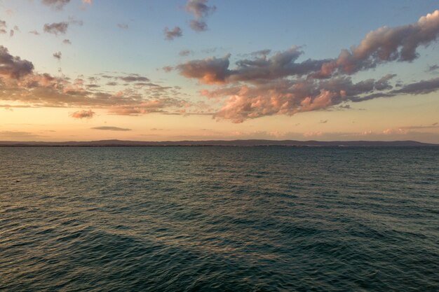 Meeresoberfläche mit blauen Wasserwellen unter gelbem und lila Sonnenuntergangshimmel.