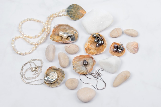Meeresschmuckkollektion auf hellem Marmor mit Muscheln und Kieselsteinen