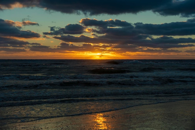 Meeressonnenunterganglandschaft mit weichen abendlichen Meerwasserwellen, die am Sandstrand zerquetschen