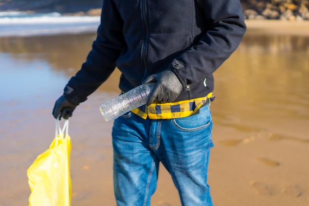 Meeresverschmutzung nicht erkennbarer Freiwilliger, der Plastik auf dem Strandökologiekonzept sammelt