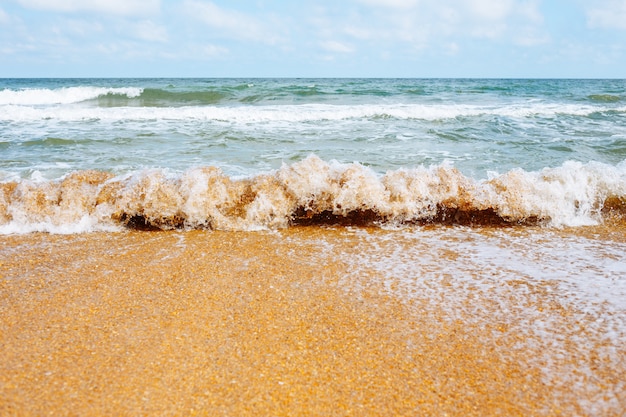 Meereswelle läuft an einem Sandstrand.