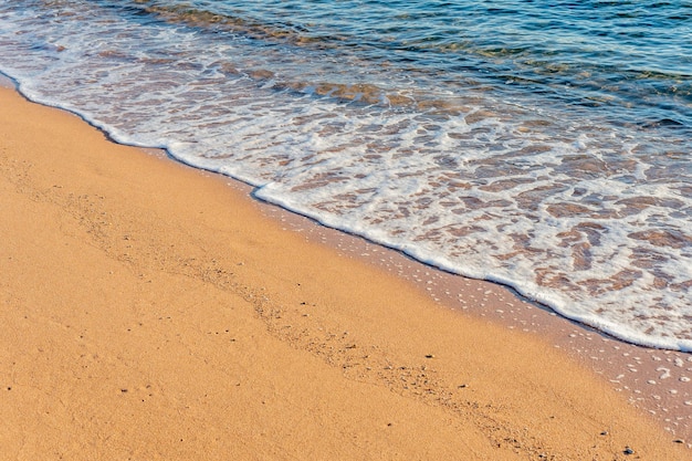 Meereswelle mit Schaum am Sandstrand