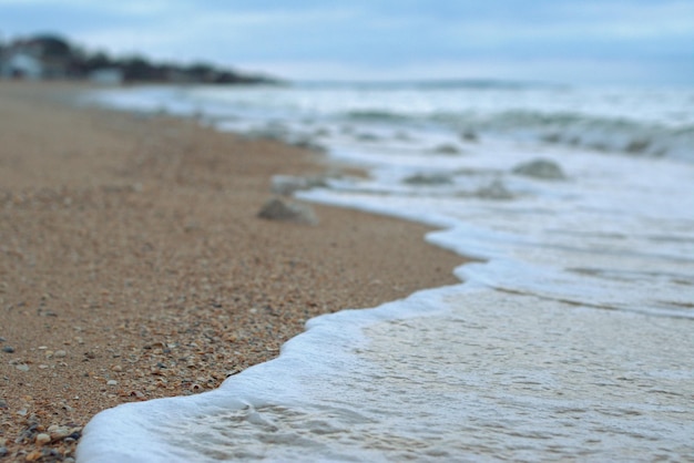 Meereswelle rollt entlang der Küste eines Sandstrandes Herbstaufnahmen der Meereslandschaft verschwommener Hintergrund selektiver Fokus Asowsches Meer Russland