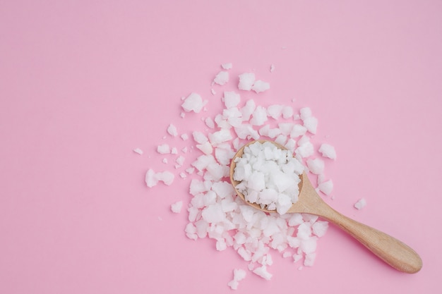 Meersalz in einem Holzlöffel auf rosa Hintergrund