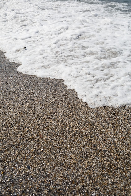 Meerwasser von einer Welle mit Schaum an der Küste