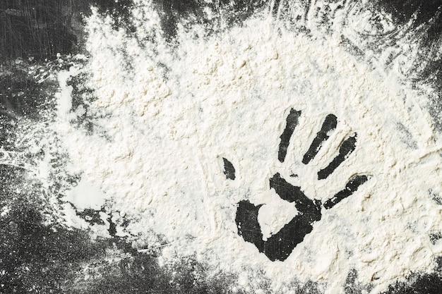 Mehl auf der schwarzen Oberfläche mit Handzeichen