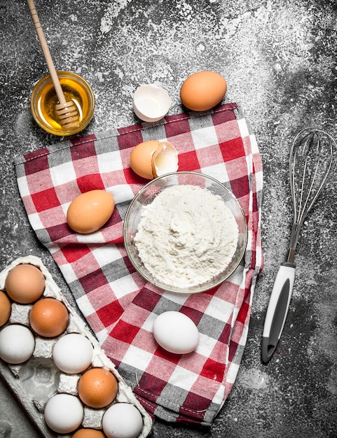 Mehl und frische Eier zum Backen auf rustikalem Hintergrund