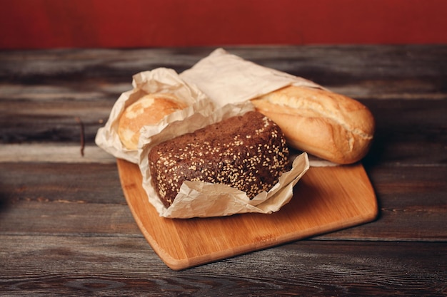 Mehlprodukte gebackenes Brot auf Holzbrett und roter Hintergrund im Hintergrund