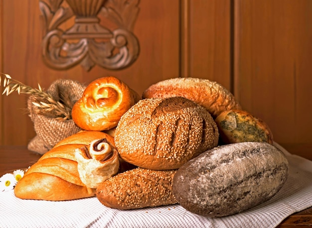 Mehlprodukte verschiedener Art Weidenkorb mit verschiedenen Brotsorten und süßen Brötchen auf einem Holztisch