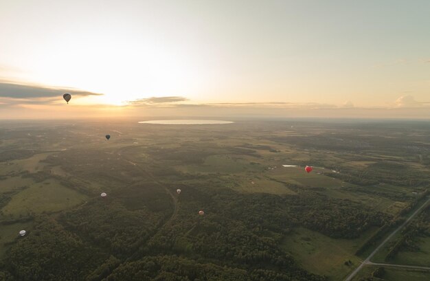 Mehrere bunte Luftballons fliegen über das Feld mit Wärmetechnik am Abendhimmel