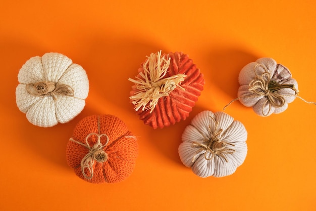 Mehrere hausgemachte Kürbisse für Halloween-Urlaubsdekor gestrickte und Stoffkürbisse auf orangefarbenem Hintergrund