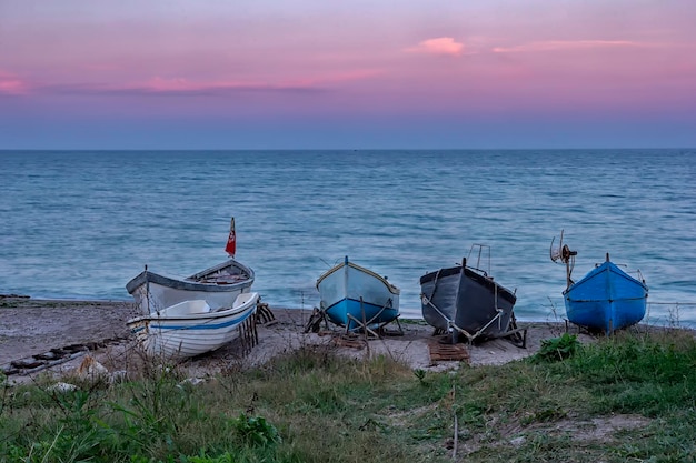 Mehrere Holzboote im Sand nach Sonnenuntergang