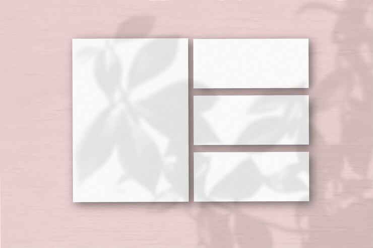 Foto mehrere horizontale und vertikale blätter aus weißem strukturiertem papier auf dem hintergrund einer rosa wand. natürliches licht wirft schatten von einer exotischen pflanze. flache lage, ansicht von oben. horizontale ausrichtung