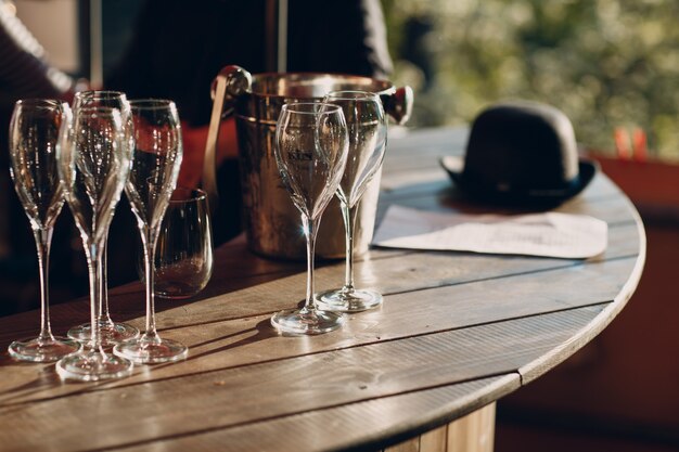 Mehrere leere schöne Glasweingläser stehen mit Blendung von der Sonne auf dem Tisch.