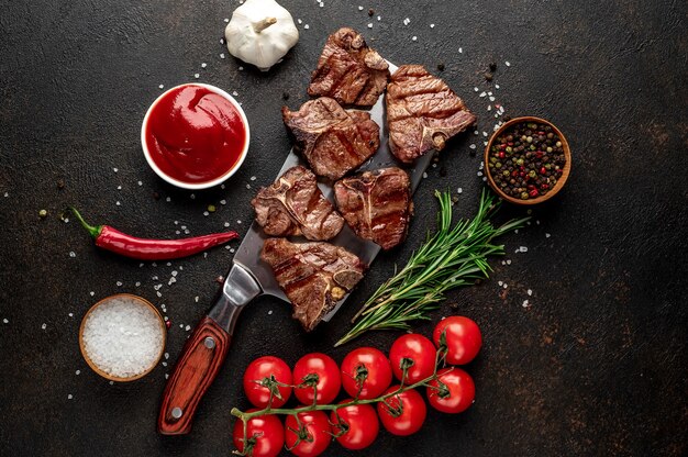 mehrere Mini-T-Bone-Steaks vom gegrillten Rindfleisch auf dem Messer auf dem Steintisch