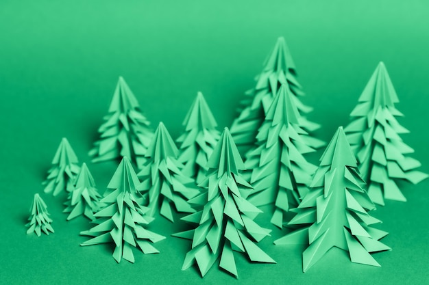 Foto mehrere papier-weihnachtsbäume, die mit der origami-technik auf einem grünen papierhintergrund hergestellt wurden