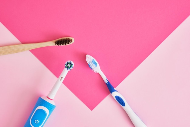 Mehrere verschiedene Arten von Zahnbürsten auf rosafarbenem Hintergrund
