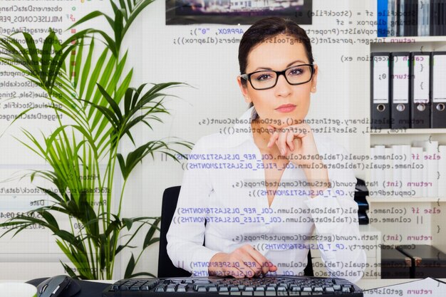 Mehrfache Exposition einer mittleren erwachsenen Geschäftsfrau und Codierung im Büro