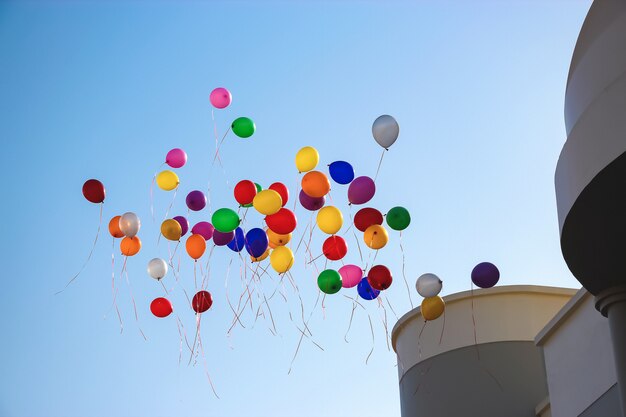 Mehrfarbenballone fliegen hohen klaren blauen Himmel nahe Schule.