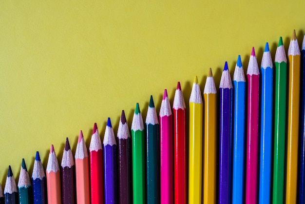 Mehrfarbige Bleistifte auf gelbem Hintergrund isoliert. Bunte Zeilenkurve von Buntstiften, Farbstiften, zurück zur Schule. Bunte Holzstifte