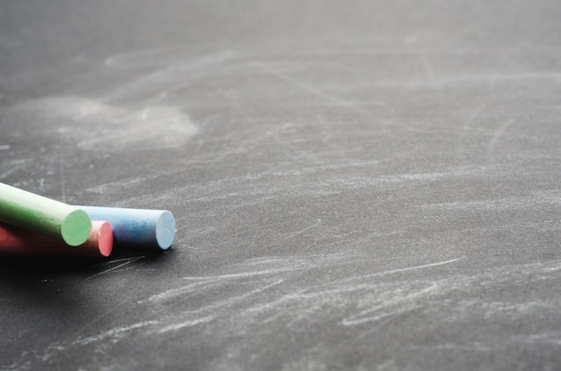 Mehrfarbige Buntstifte auf einer bemalten Tafel. Schulbehörde, konzeptioneller Hintergrund. Kopieren Sie Platz, Nahaufnahme.