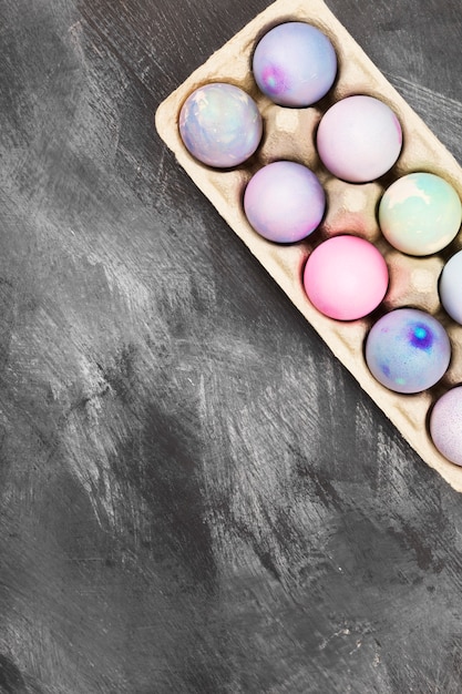 Mehrfarbige Eier für Ostern im Behälter für Eier auf schwarzem Hintergrund. Draufsicht, Kopierraum. Lebensmittelhintergrund